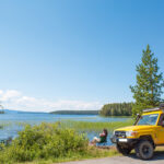 Finnland Pielinenroute Frau vor einem gelben Camper am See