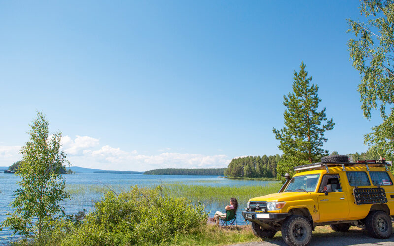 Finnland Pielinenroute Frau vor einem gelben Camper am See