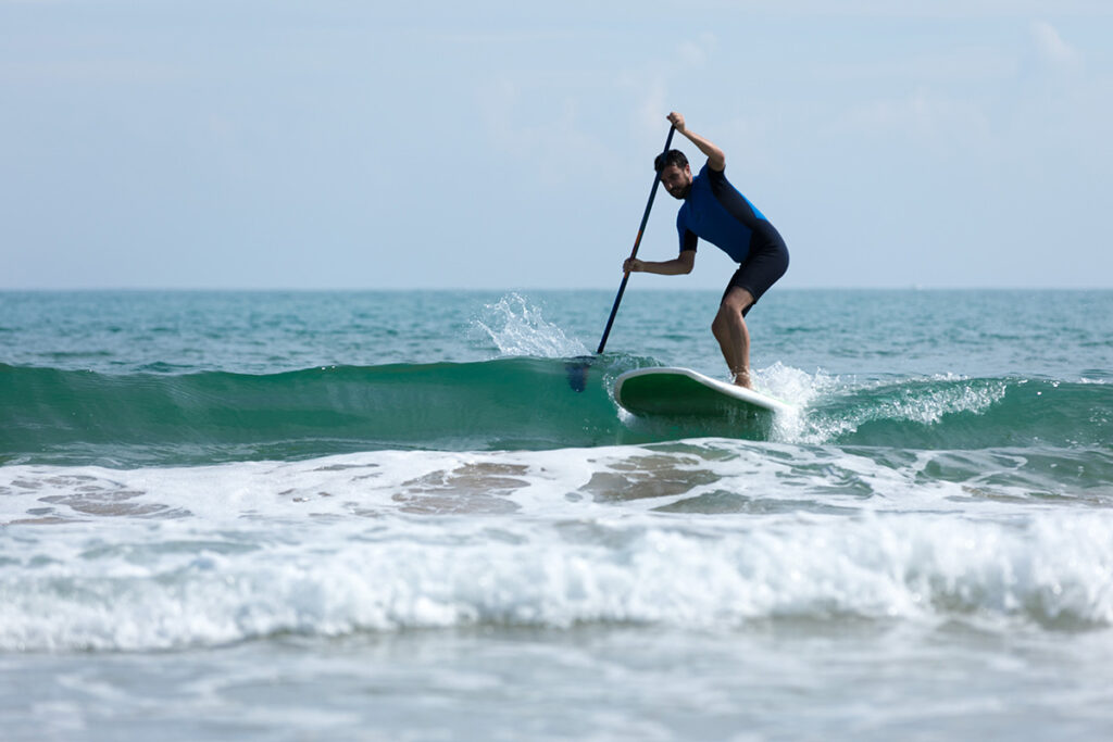 SUP Paddler reitet eine Welle in der Bucht von Valencia